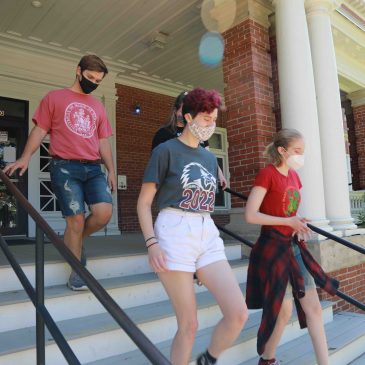 Students in face masks walking from a UMF residence hall entrance